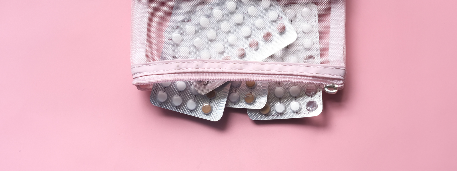 A close-up of blister packs containing white birth control pills resting on a pink background. The image symbolizes traditional hormonal birth control in comparison to natural cycle tracking with trackle.